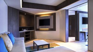 A modern living room with a sofa, a coffee table, and a TV mounted on the wall. - Grand Mercure Jakarta Kemayoran (Jakarta)