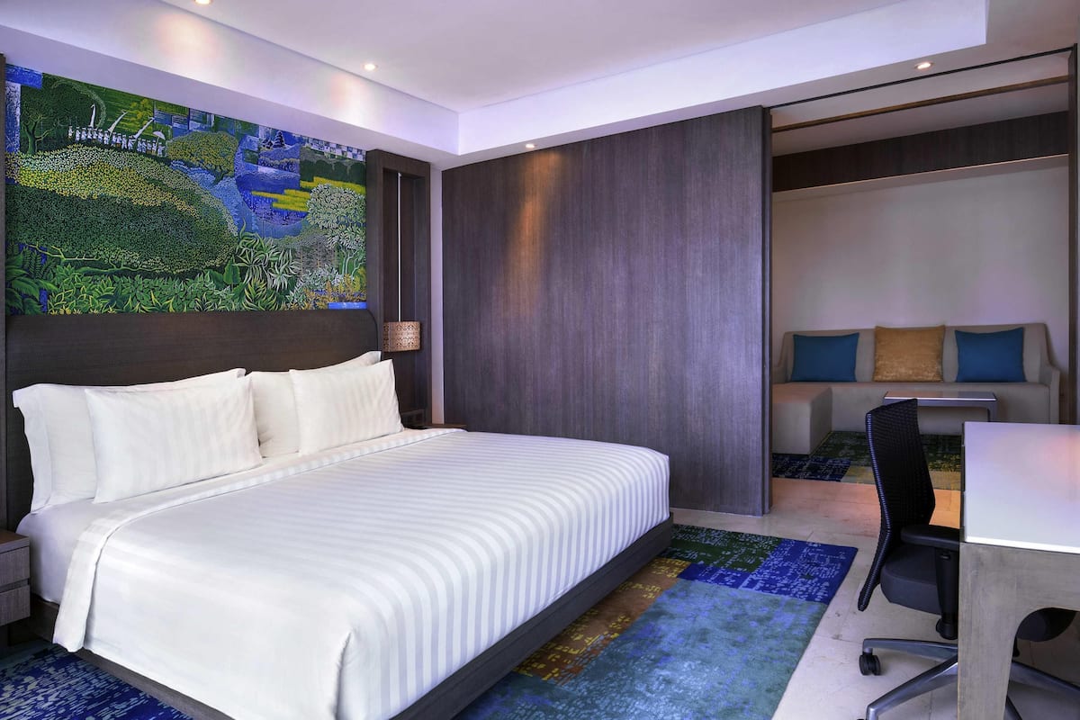A modern hotel room with a large bed, a desk, and a chair.
