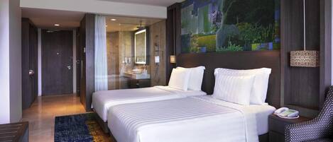 Habitación de hotel con una cama grande, un baño con espejo, una mesita de noche y un teléfono instalado en la pared.