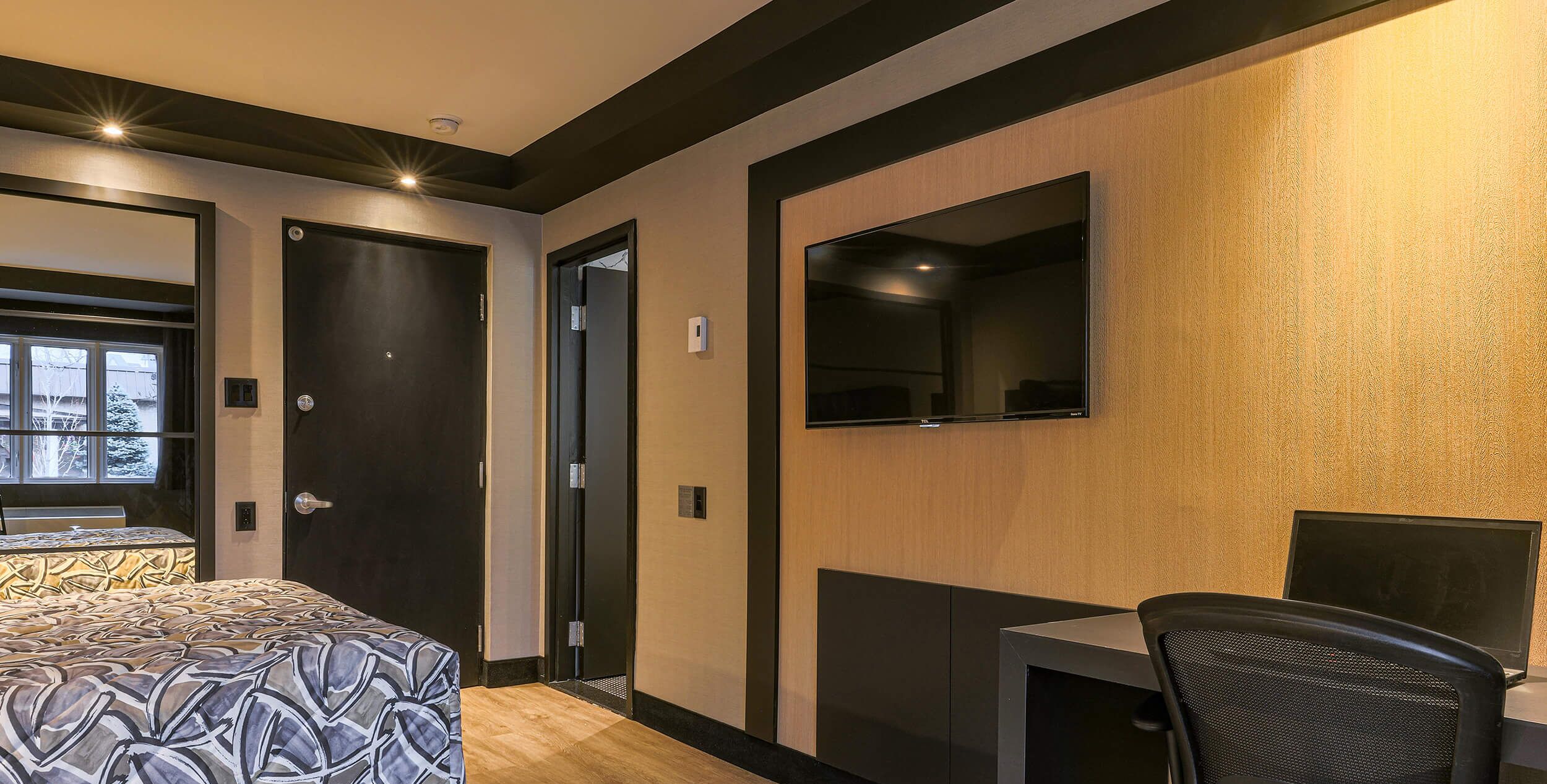 Ein Hotelzimmer mit Bett, Schreibtisch, Stuhl, Fernseher und Fenster.