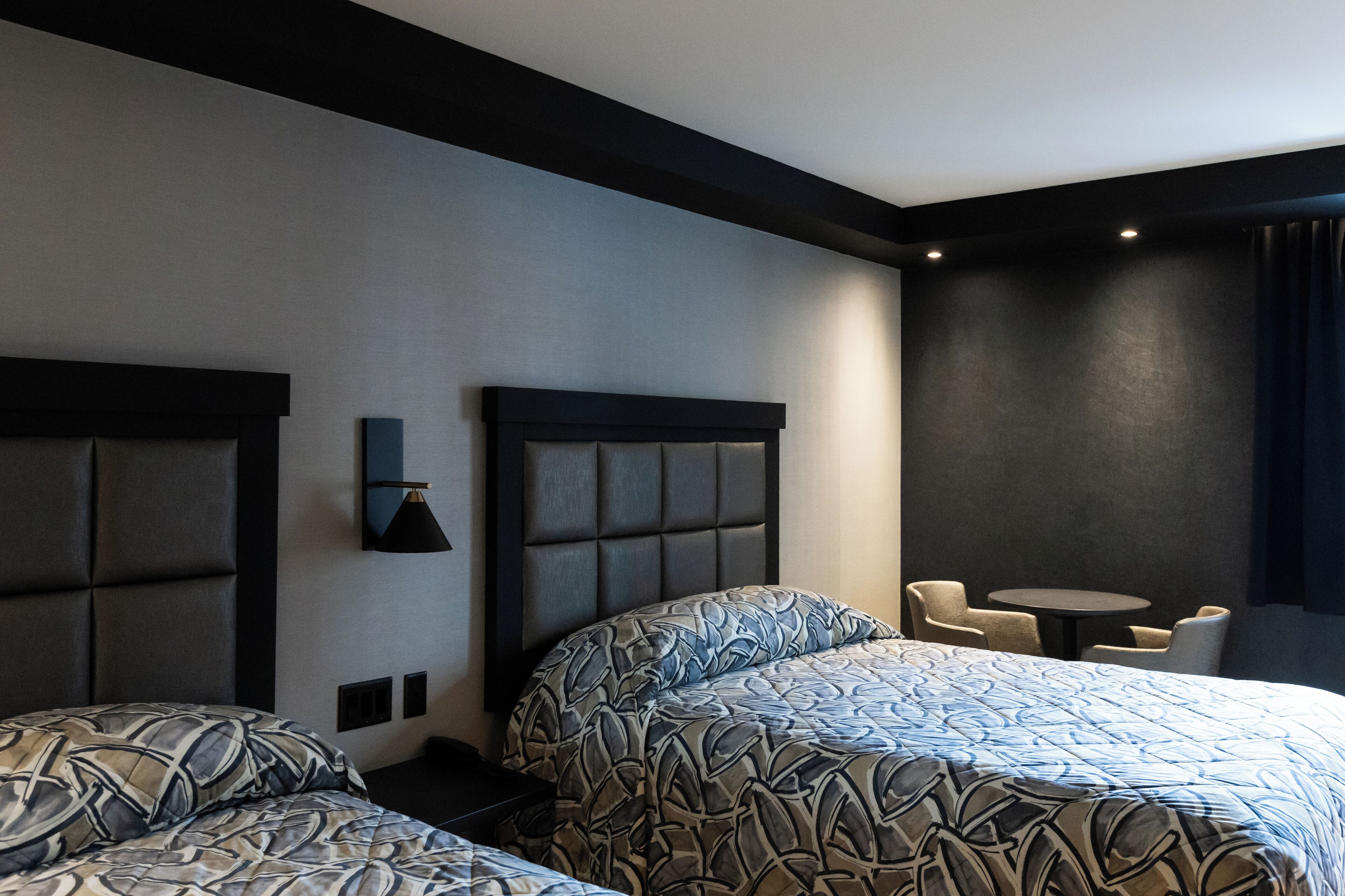 A hotel room with two beds, a small table, and a chair.