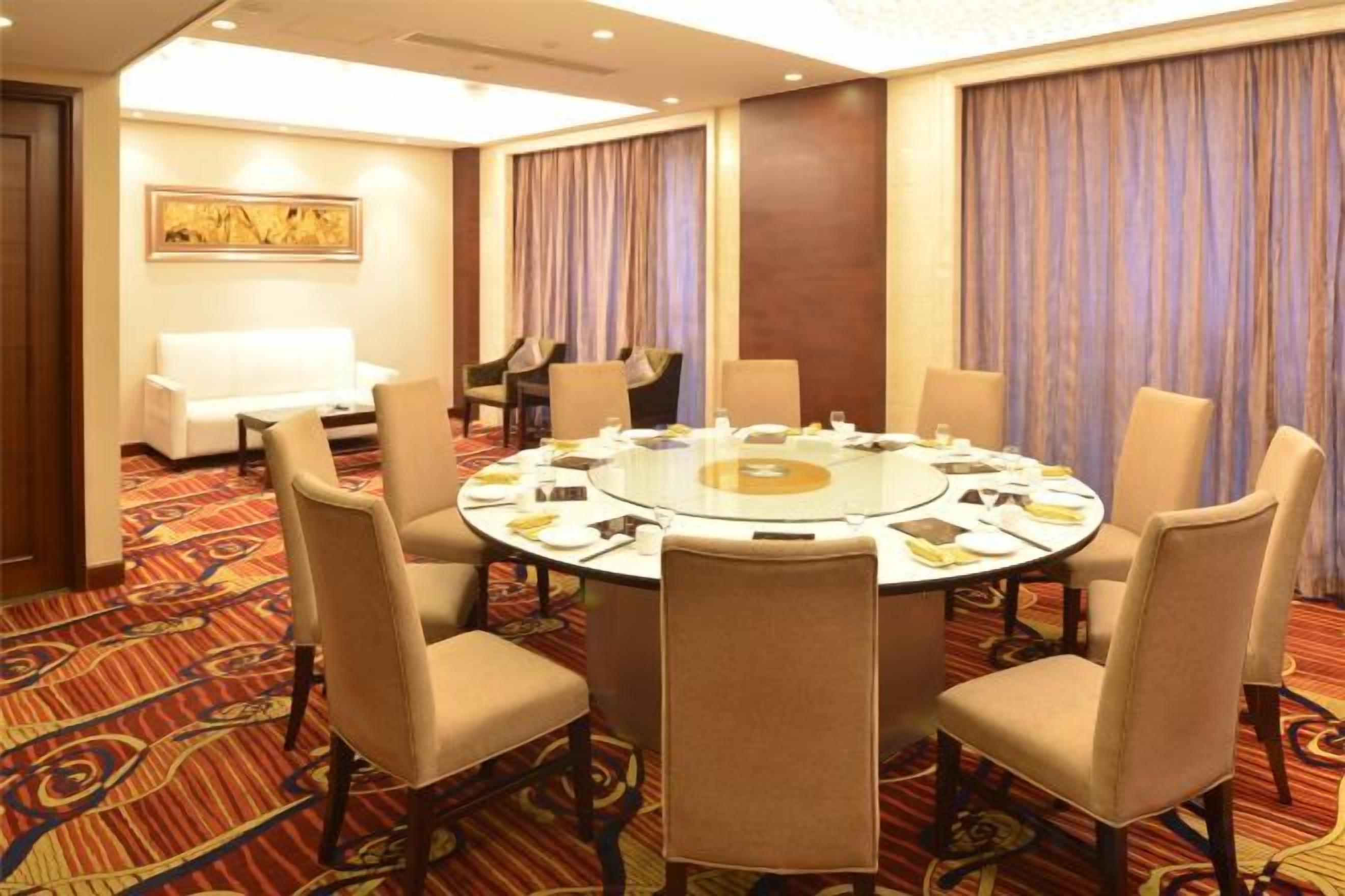 A conference room with a round table, chairs, and a piano.