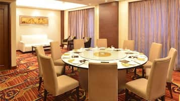 A conference room with a round table, chairs, and a piano.