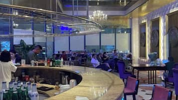 A bar area with a curved counter, seating, and a chandelier.
