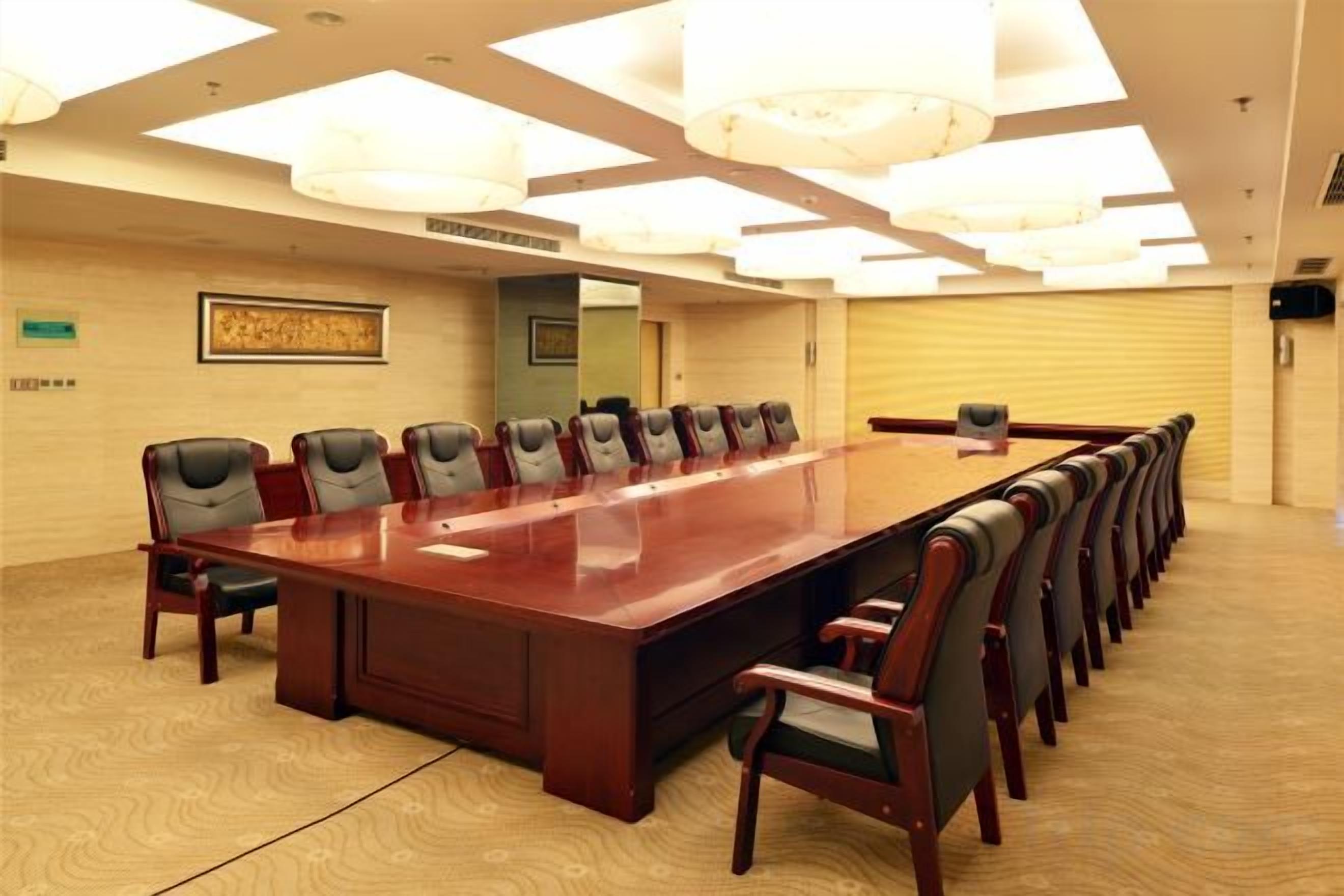 A conference room with a long table and chairs, a carpeted floor, and a ceiling with recessed lighting.