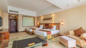 Een hotelkamer met twee bedden, een bank, een glazen salontafel en een televisie.