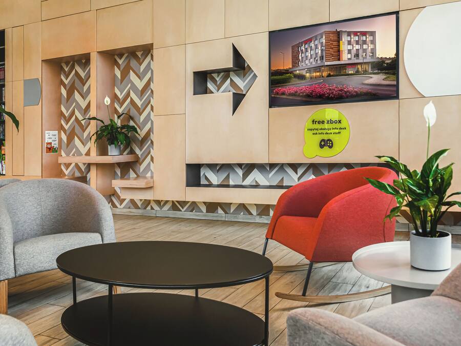 A modern reception area with a chevron-patterned wall, a Freebox Xbox sign, and a view of a building in the background.