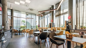 A modern dining area with large windows, high ceilings, and contemporary furniture. - Qubus Hotel Żory (Zory)