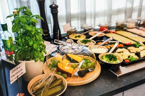 A buffet with various dishes, a potted basil plant, and a sign indicating a small salad. - Qubus Hotel Żory (Zory)