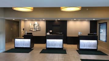 A reception area with three reception desks, a wall-mounted sign for 'Holiday Inn,' and a window with blinds.