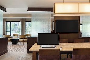 Ein Hotelkonferenzraum mit einem großen Tisch, Stühlen, einem Computer und einer Projektionsleinwand.