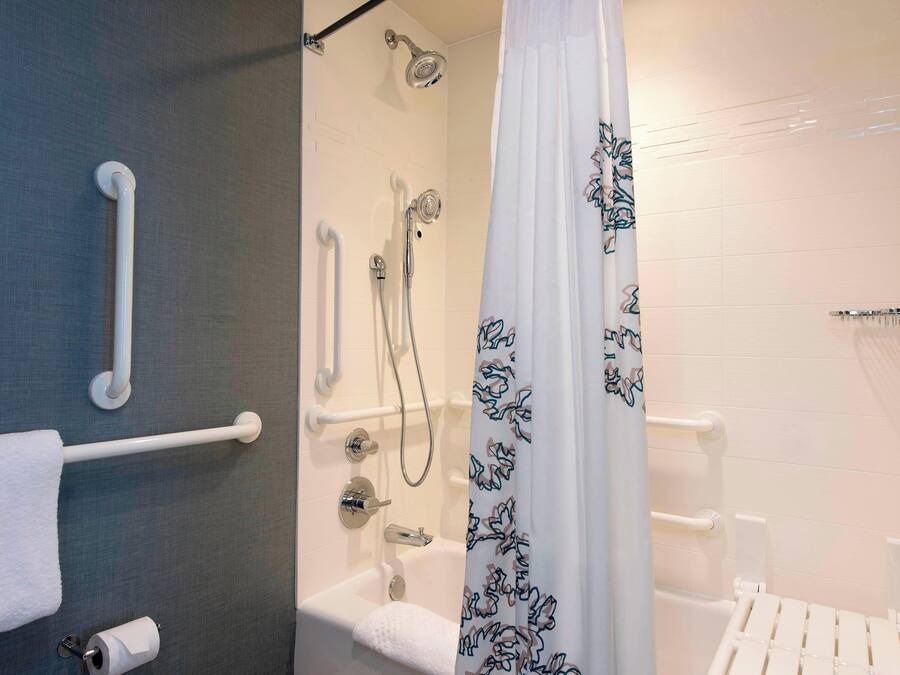 A bathroom with a shower, toilet, and grab bars.