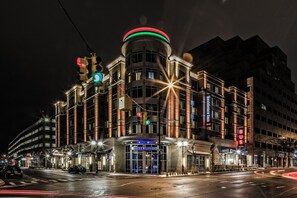 A hotel with a prominent circular sign on top, multiple floors, and a well-lit entrance.