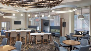 A hotel lobby with a central seating area, multiple tables, and chairs. There are large windows providing natural light, and the ceiling features a wooden panel design. - Residence Inn Ann Arbor Downtown (Ann Arbor)