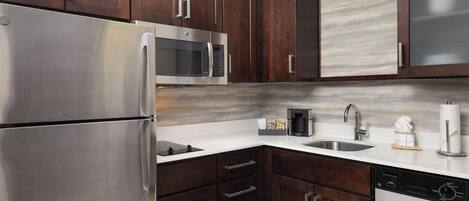 A modern kitchen with dark wood cabinets, stainless steel appliances, a microwave, and a dishwasher.