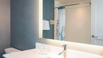 A modern bathroom with a white sink, a mirror, and a shower curtain.