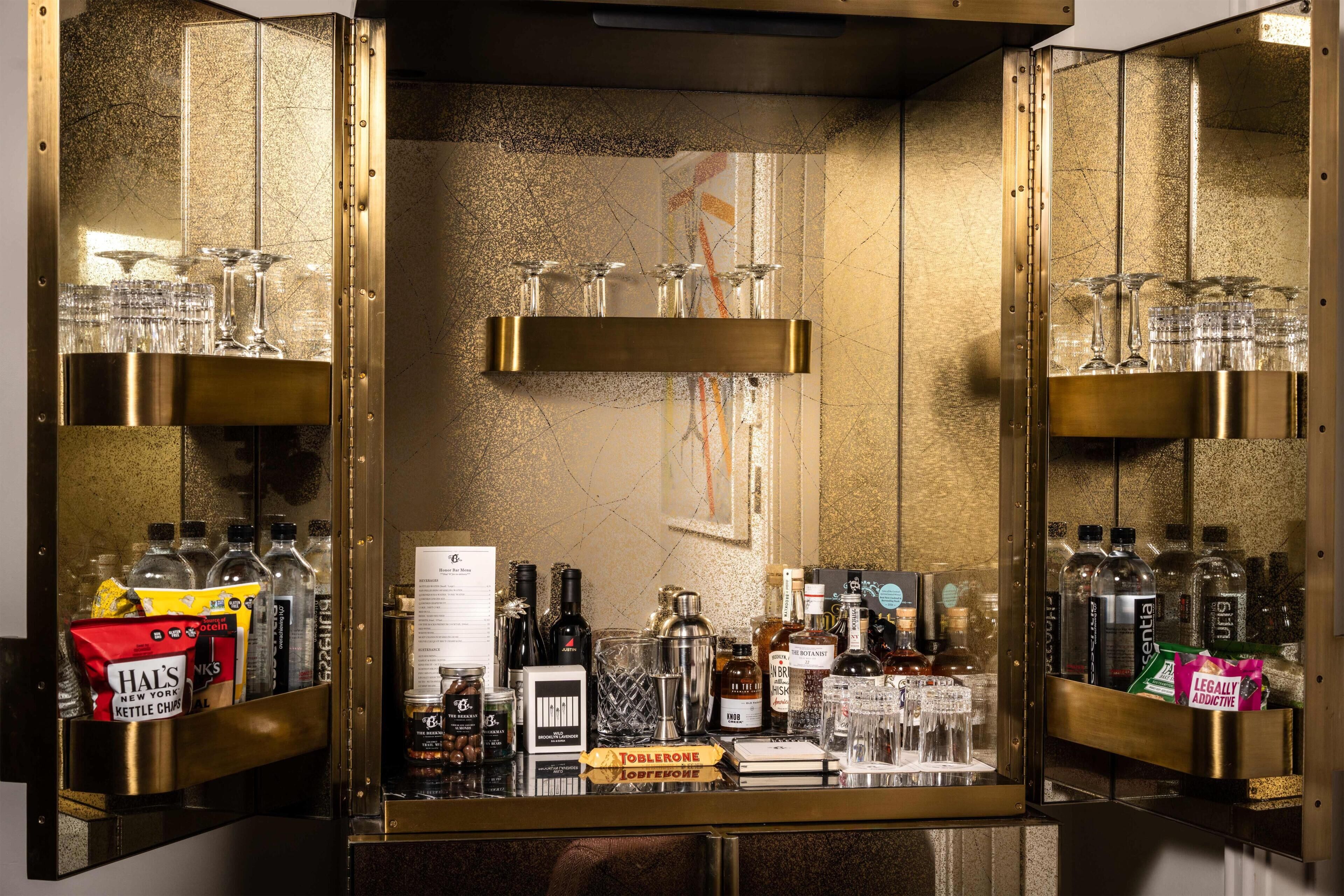 A bar area with shelves of glasses, bottles, and snacks.