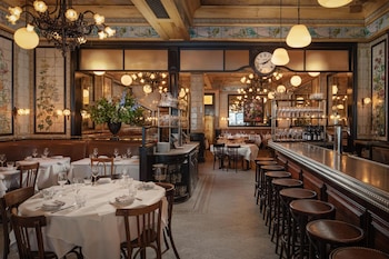 A kitchen with a wooden shelf unit above a white countertop, containing various kitchen items and bottles. at The Beekman, A Thompson Hotel, by Hyatt