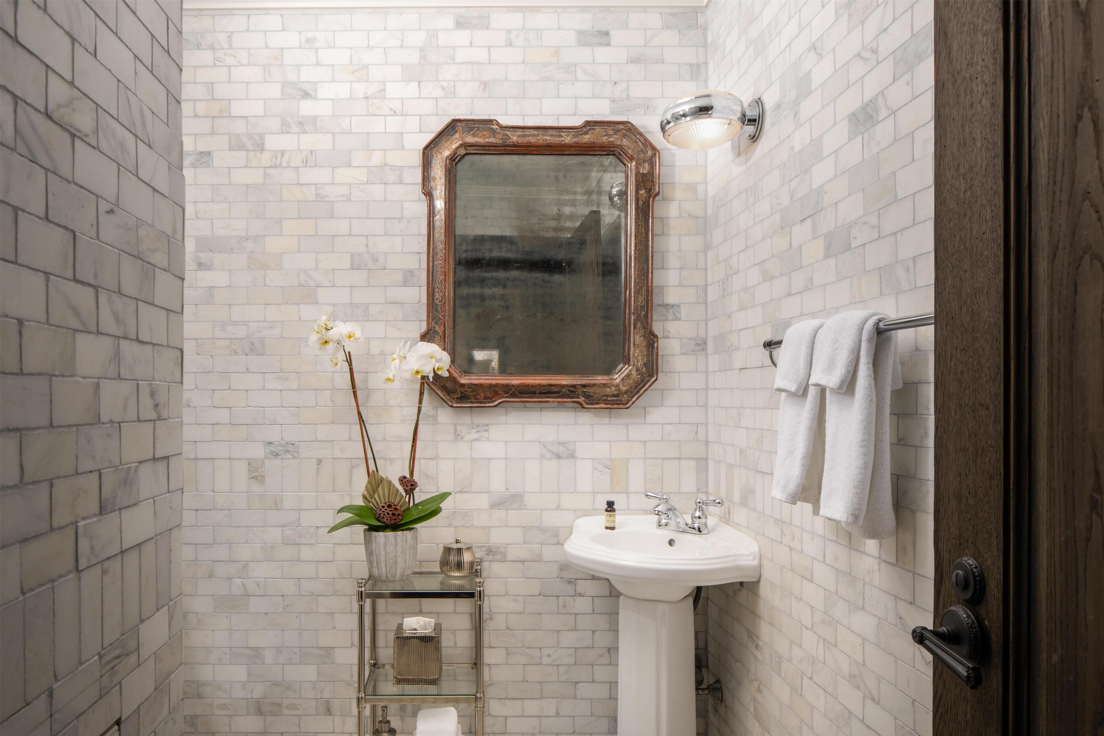 A bathroom with a white sink, a mirror, and a towel rack.