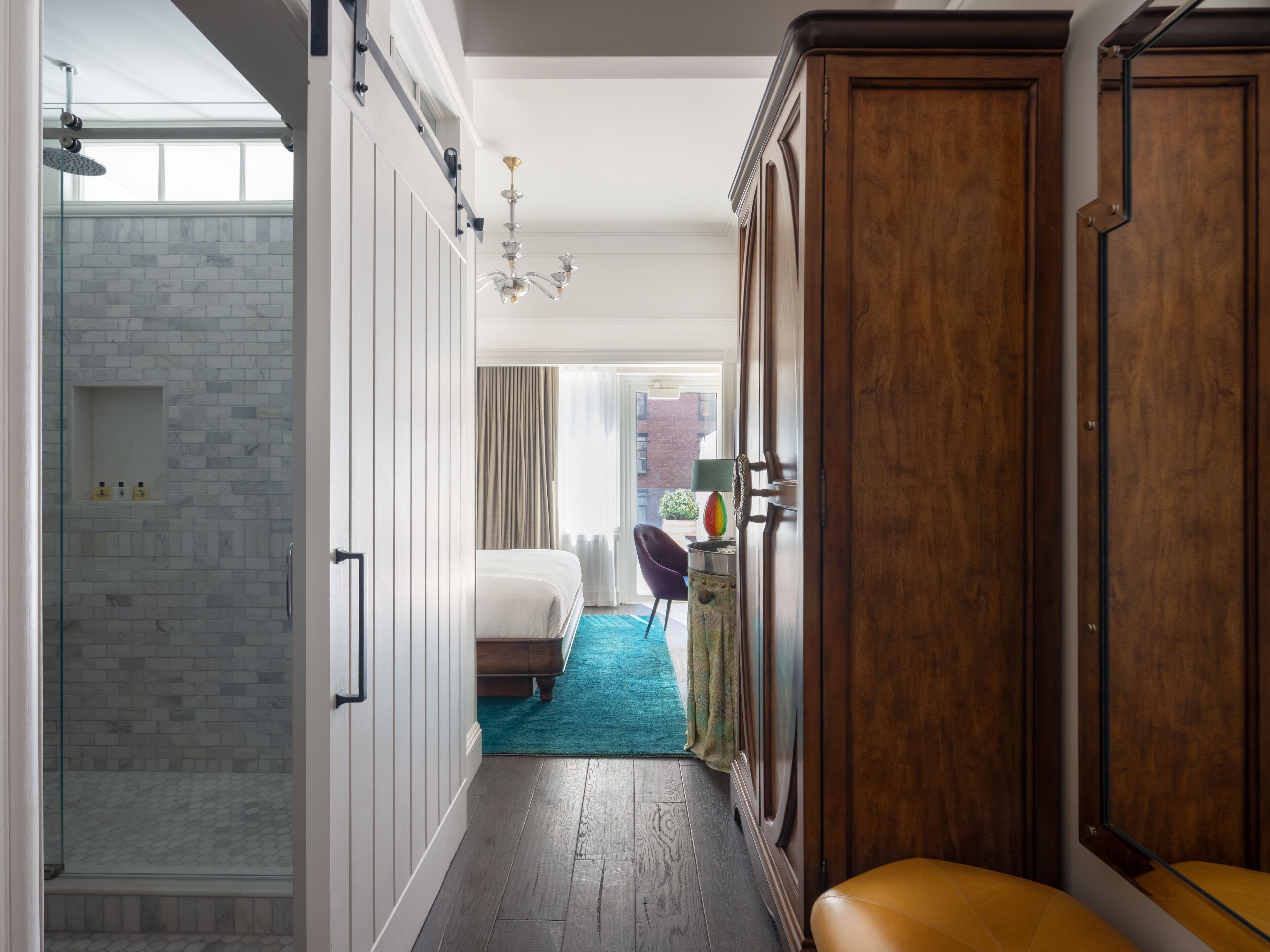 Habitación de hotel con ducha, cama, armario de madera y vistas a la ciudad.