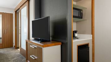 Una kitchenette compacta equipada con microondas, cafetera y un refrigerador pequeño.