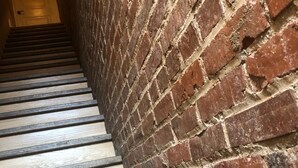 Una escalera con peldaños de madera y un muro de ladrillo.
