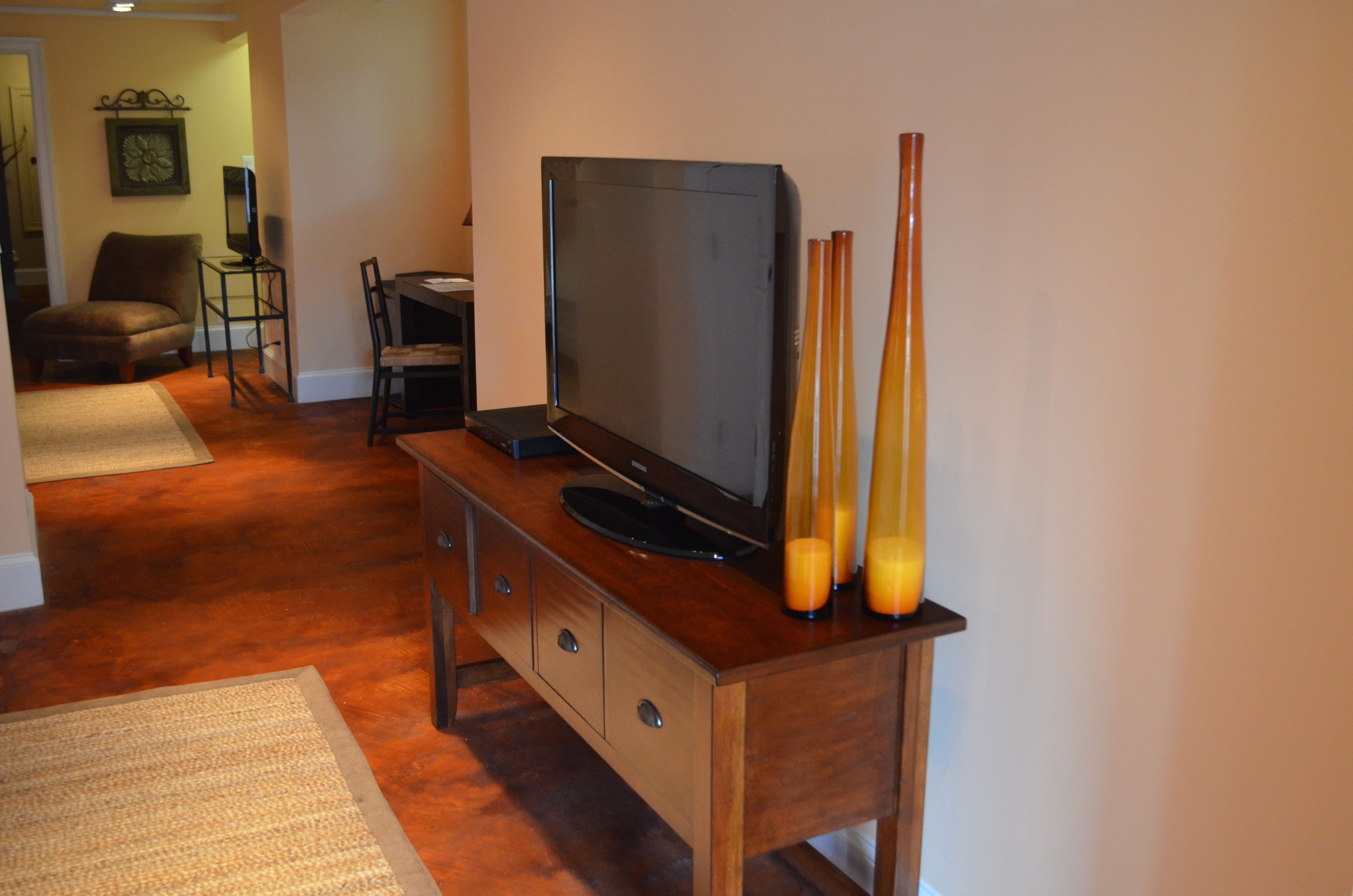 A living room with a wooden entertainment center, a flat-screen TV, and a coffee table. There are three tall candles on the table.