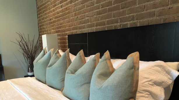 Una cama bien hecha con varias almohadas y un cabecero negro.