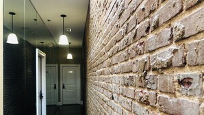 Un pasillo con suelo de madera, pared de ladrillo y puertas.