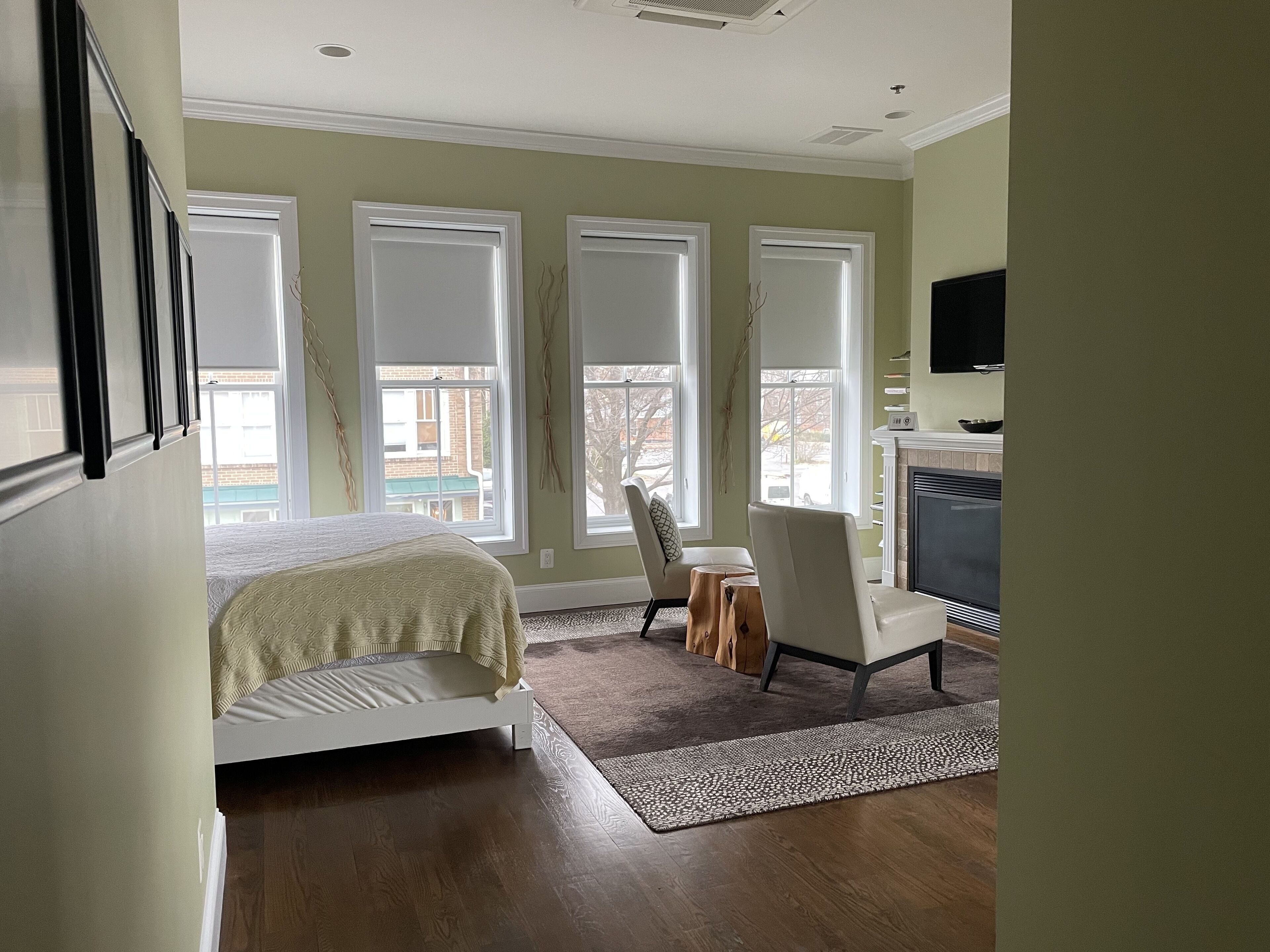 A bedroom with a bed, a desk, and a fireplace.