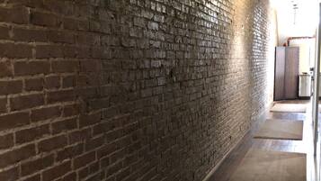 Un pasillo con pared de ladrillo, suelo de madera y una lámpara colgante.