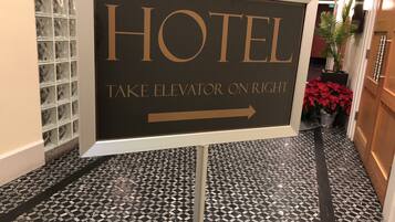 A hotel sign indicating the direction to the elevator.
