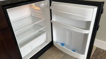 Avoin jääkaappi, jossa on useita hyllyjä ja erillinen pakastinosa.