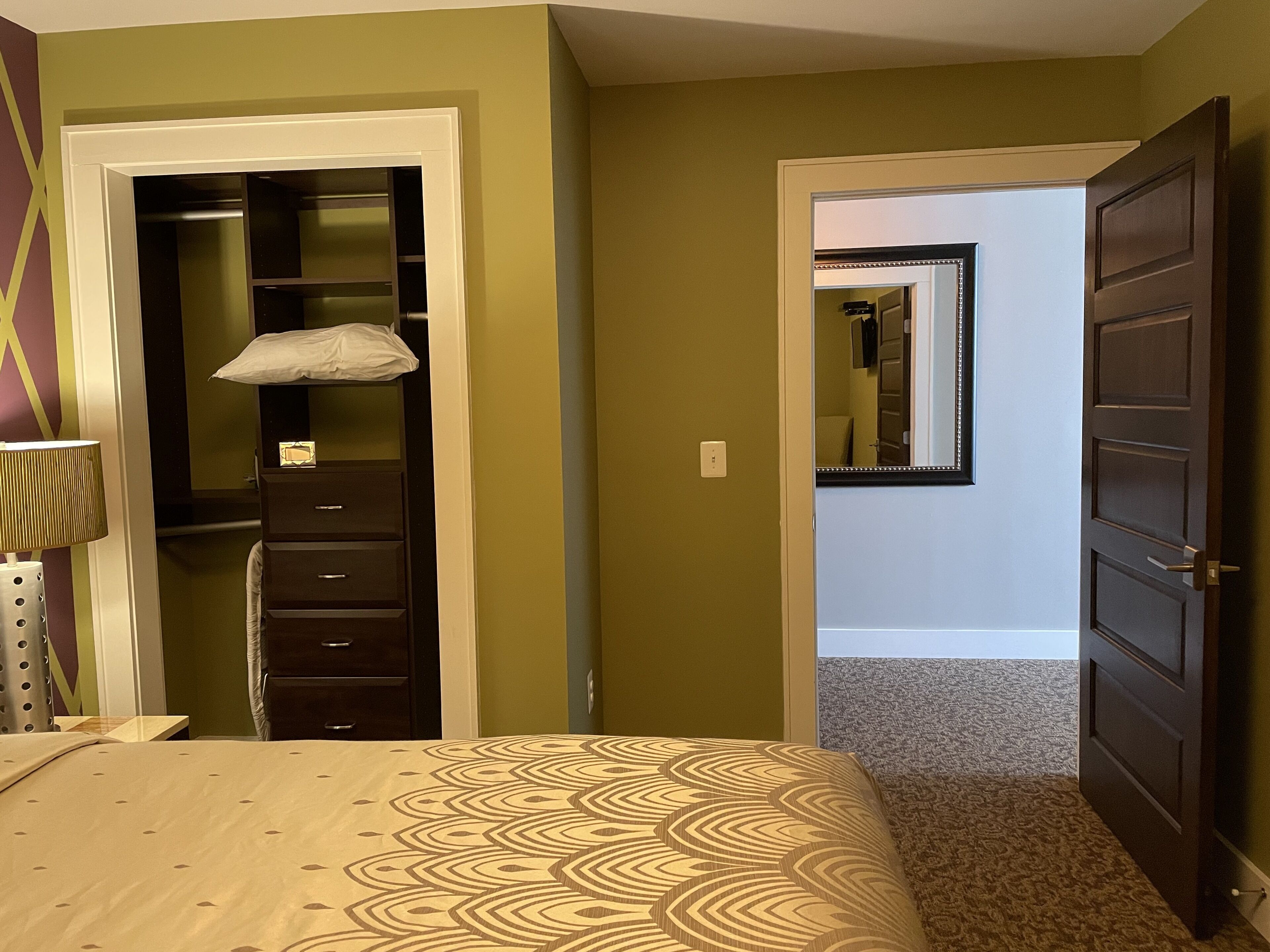 Een slaapkamer met een bed, een kledingkast en een deur naar een andere kamer.