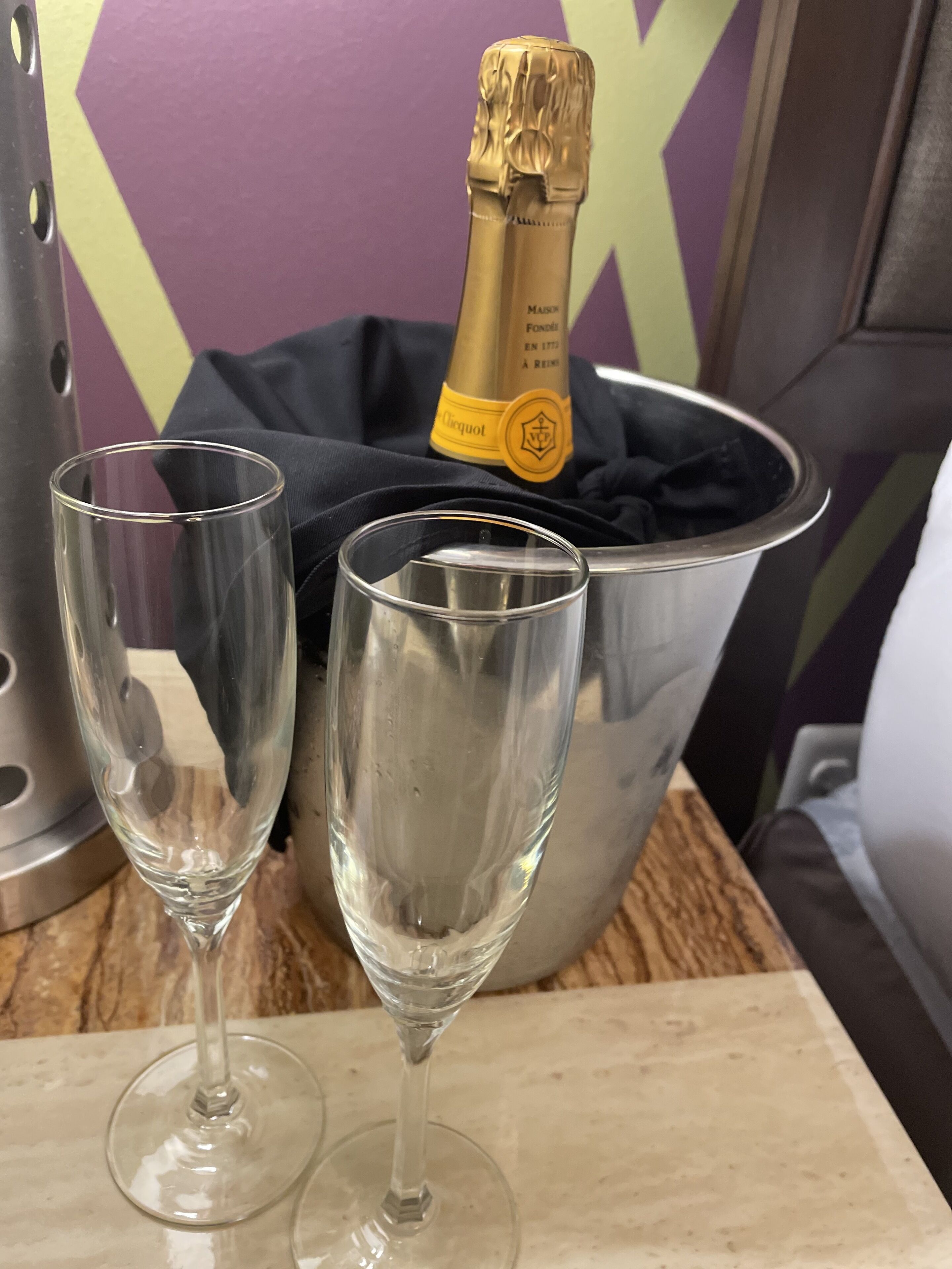 Dos copas de champán vacías sobre una mesa con una botella de champán en un cubo.