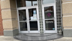 Entrada de hotel con puerta de cristal, rampa accesible para sillas de ruedas y cartel con el nombre del hotel.