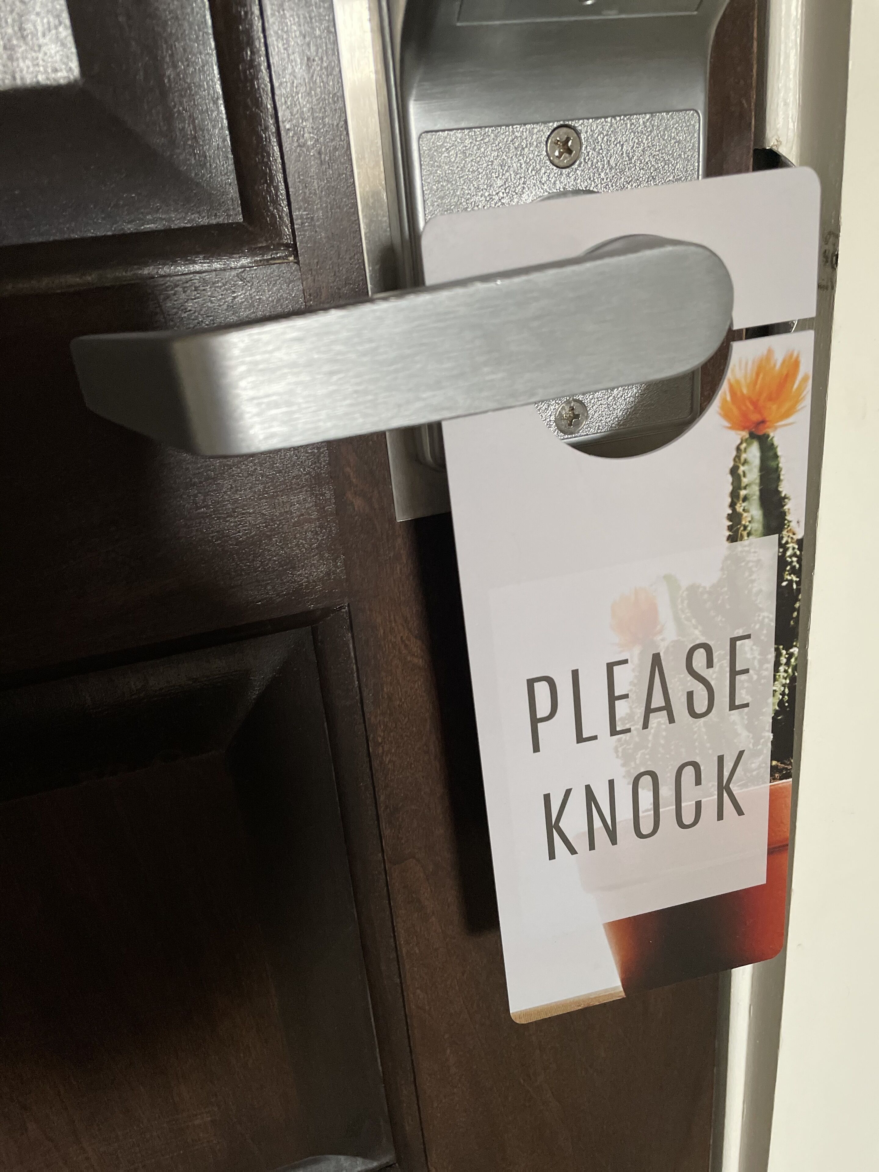 A door with a 'Please Knock' sign and a door handle.