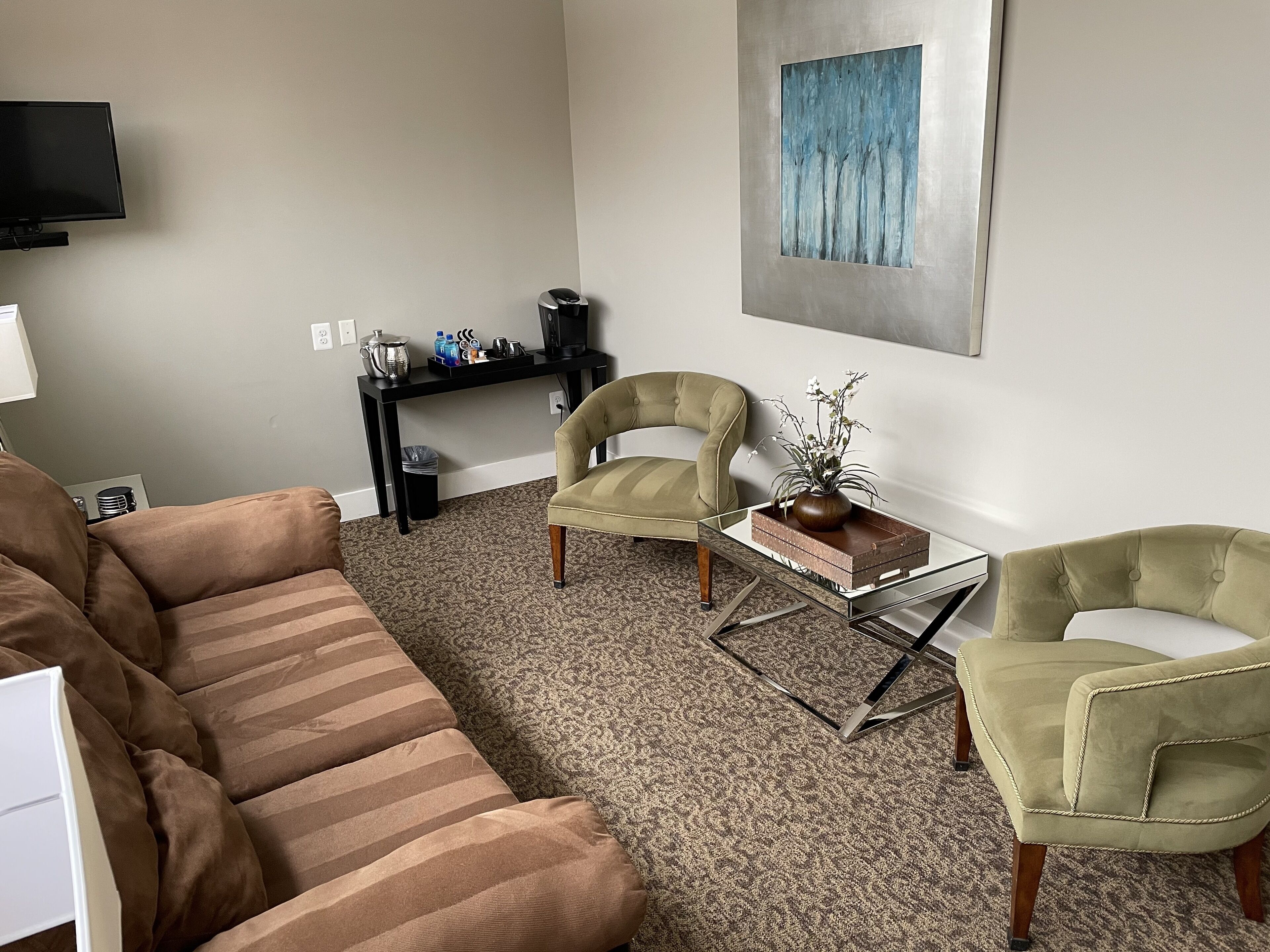 A living room with a sofa, two armchairs, a coffee table, and a painting on the wall.
