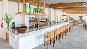A bar area with a long counter, multiple seating options, and a variety of bottles and glasses.