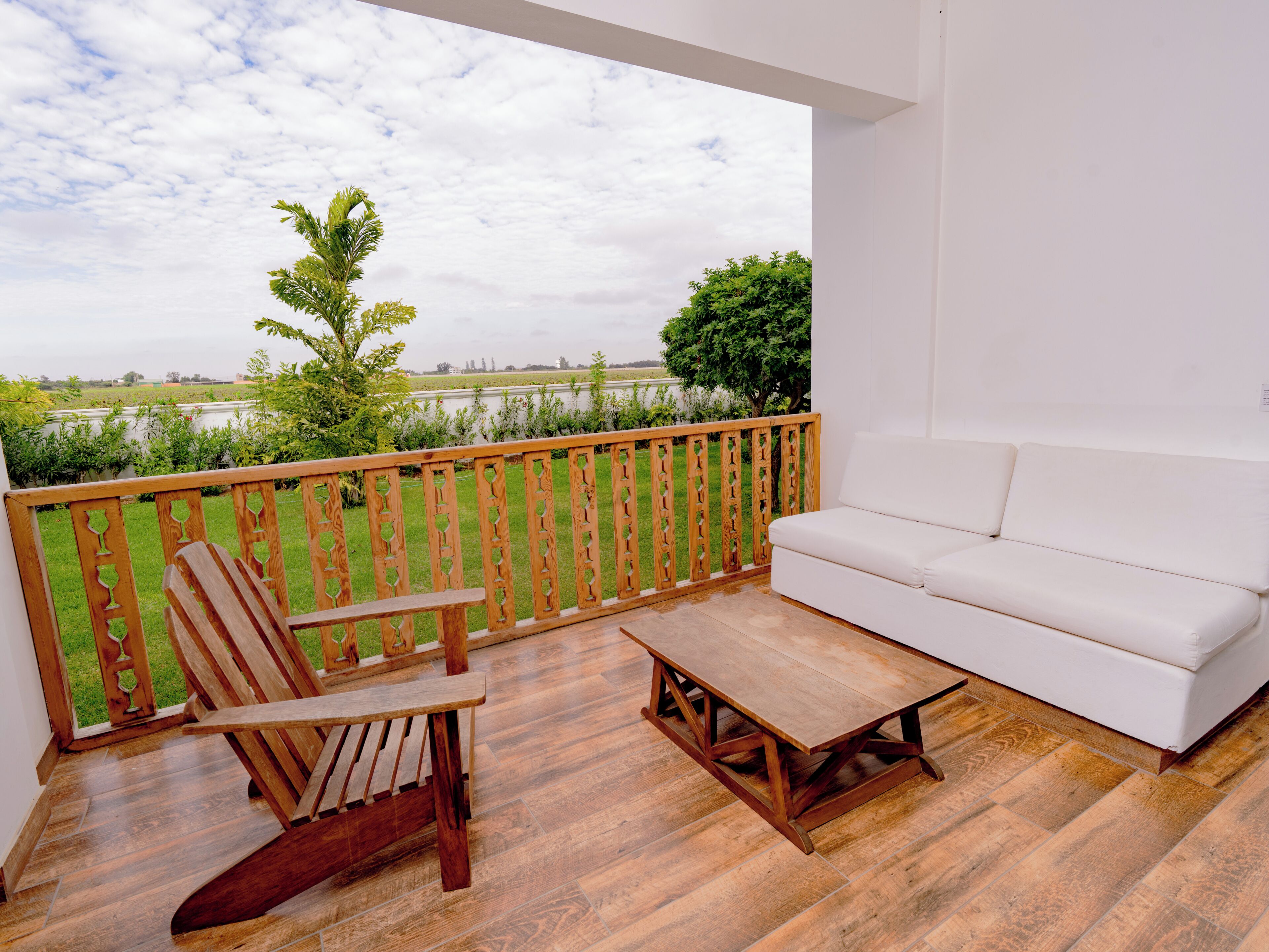 A balcony with a wooden chair, a white sofa, and a wooden table.