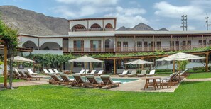 A resort with a pool, sun loungers, and a building with multiple balconies.