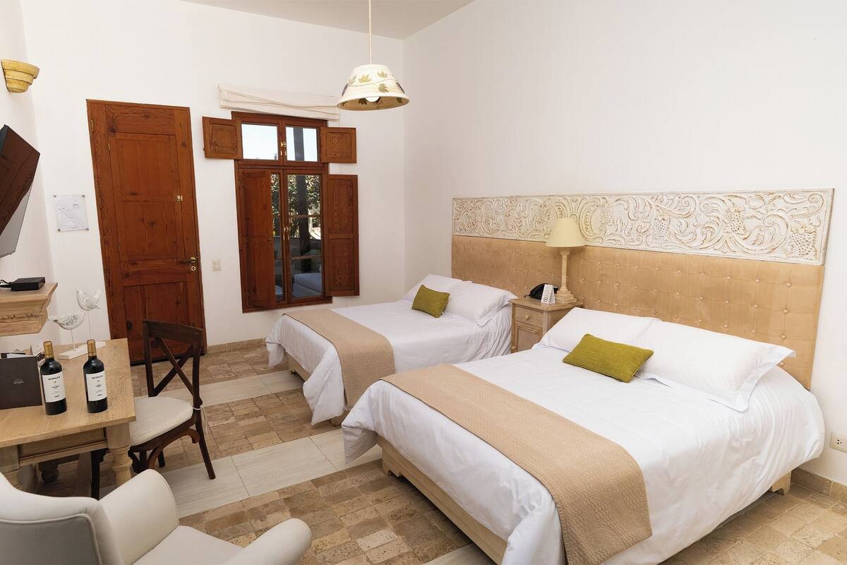 Une chambre d’hôtel avec deux lits, un bureau avec une chaise, une télévision et une fenêtre donnant sur un beau paysage.