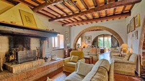 Una sala de estar acogedora con chimenea, asientos cómodos y un arco que da a otra habitación.