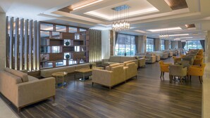 A spacious lobby with a modern design, featuring sofas, a coffee table, and a large bookshelf. - Side Sunport Hotel & Spa - All Inclusive (Manavgat)
