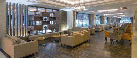 A spacious lobby with a modern design, featuring sofas, a coffee table, and a large bookshelf.
