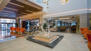 A spacious lobby with a modern design, featuring a central sculptural installation, seating areas, and a view of the outside. - Side Sunport Hotel & Spa - All Inclusive (Manavgat)