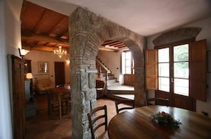 A rustic dining area with a stone archway, wooden table, and chairs.