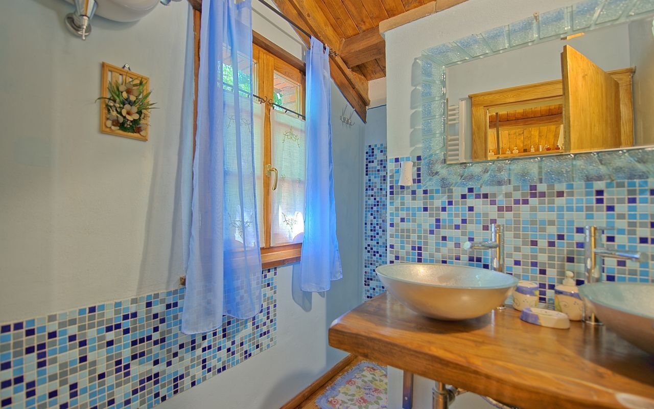 A bathroom with a wooden vanity, a large mirror, and a mosaic tile backsplash.