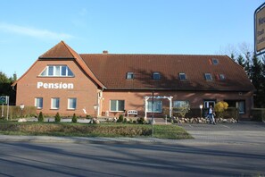 Een pension met een gevel van rode baksteen, een schuin dak en een groot raam aan de zijkant.