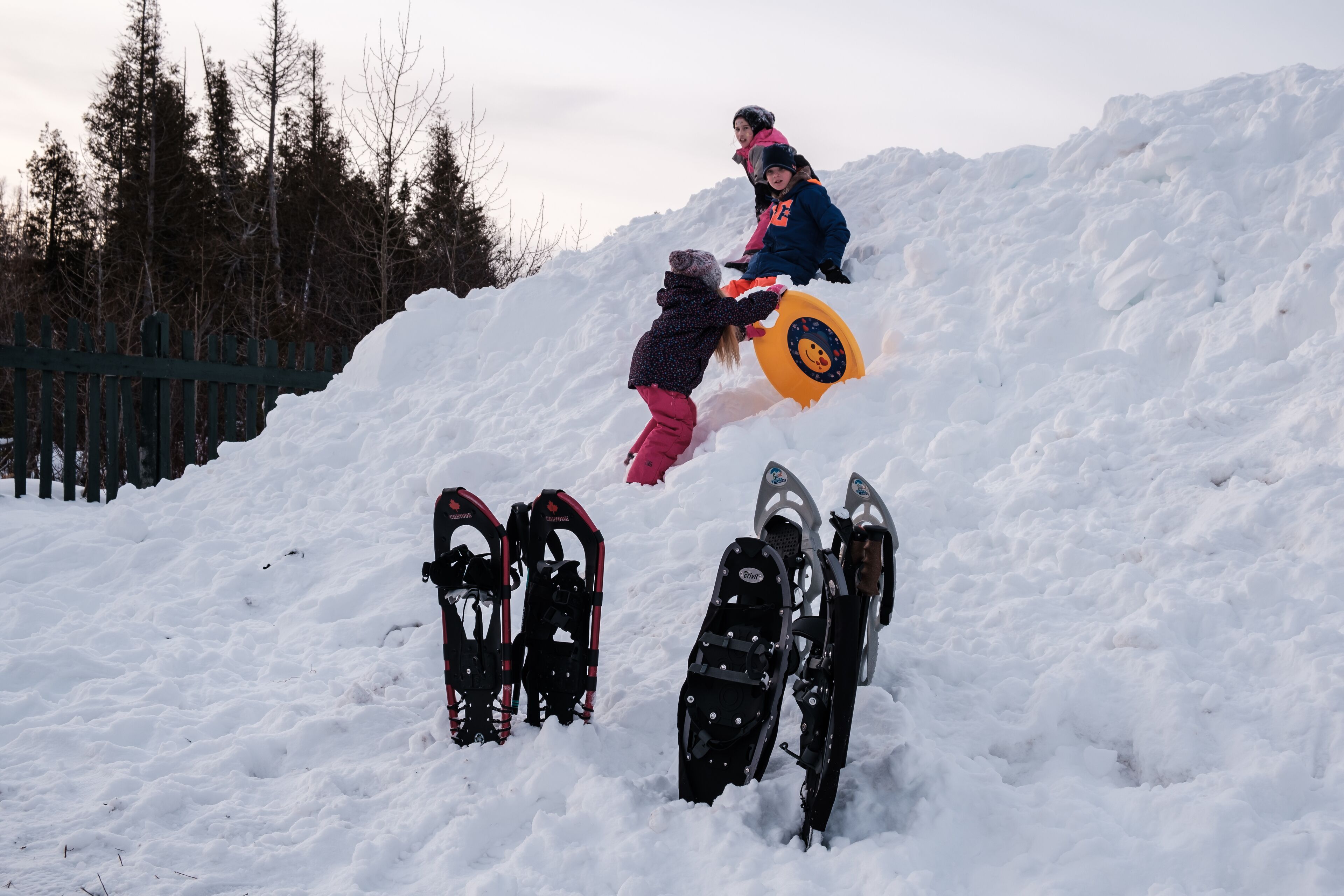 A snowy landscape with snowshoes and a snowboard.